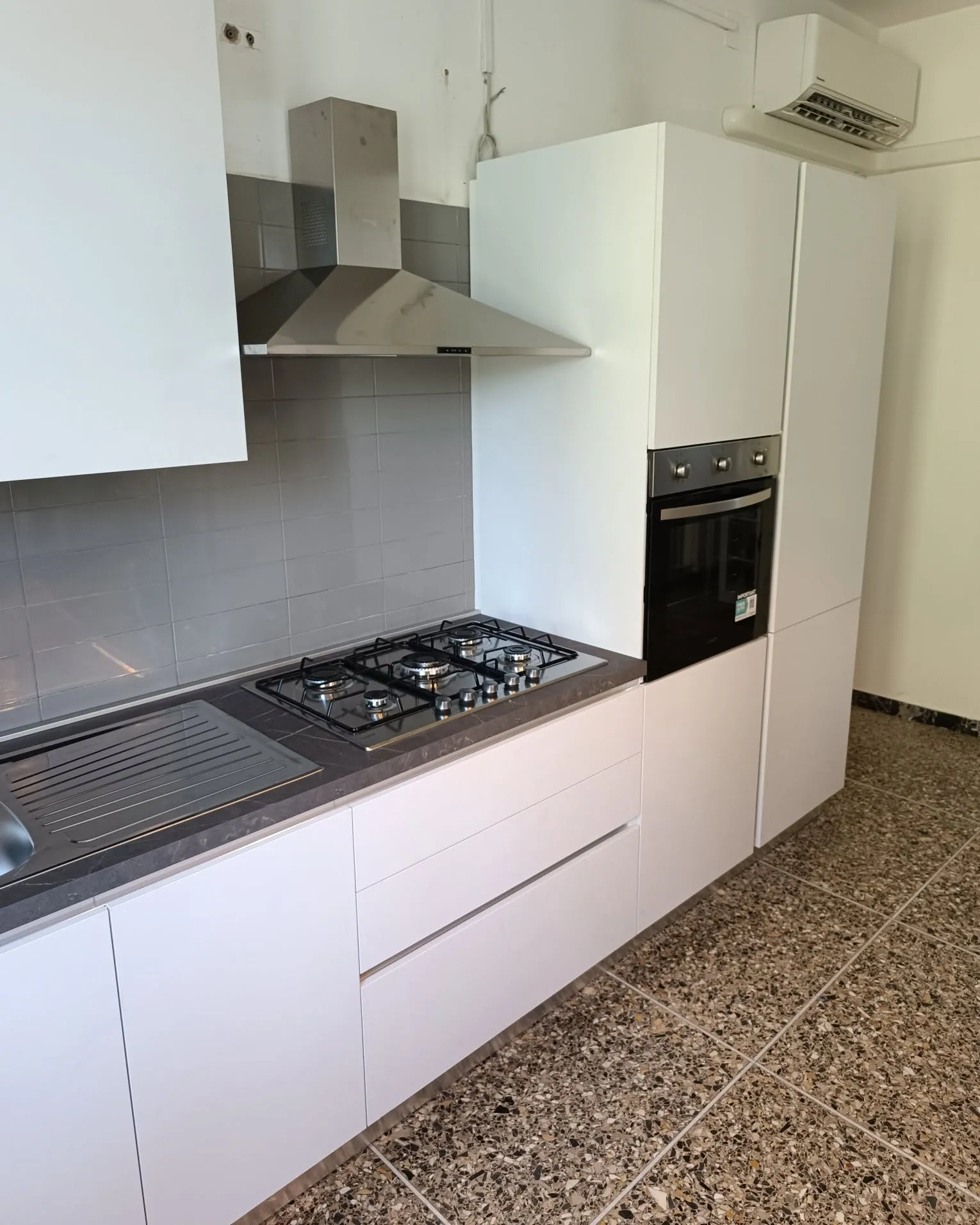 Cucina bianca ad angolo con colonna forno