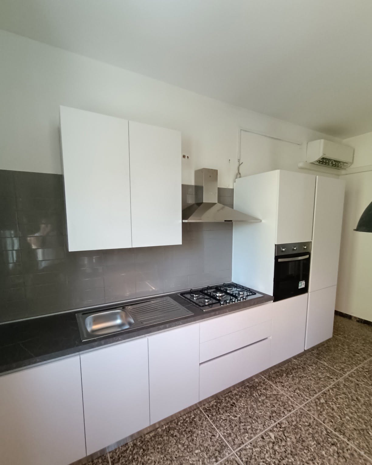 Cucina bianca ad angolo con colonna forno