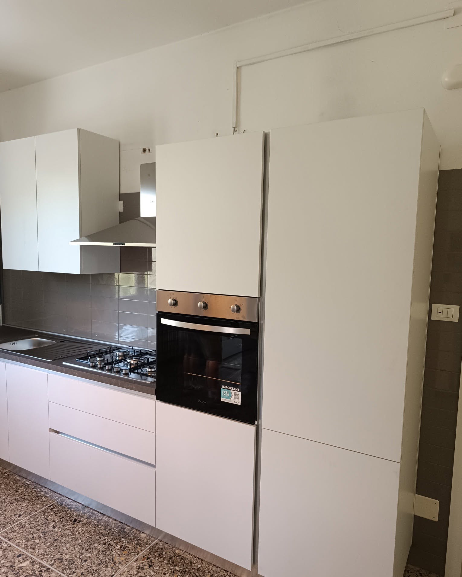 Cucina bianca ad angolo con colonna forno